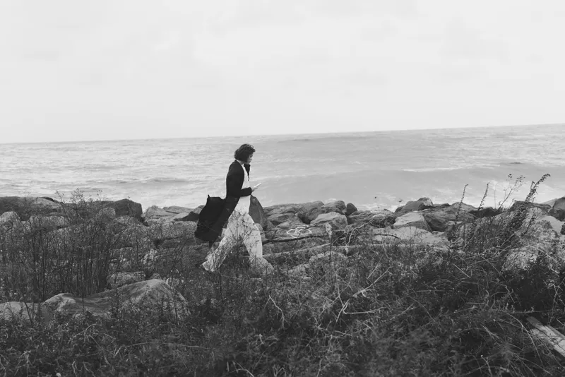 Business professional walking along a rugged coast in a suit, strolling on rocks beside the sea, silhouette against the horizon in a black and white landscape
