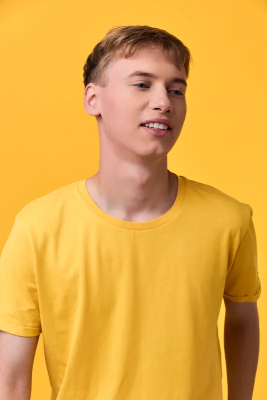 Man wearing a yellow t shirt against a bright yellow background, casual studio shot conveying warmth, confidence and relaxed mood, simple fashion style for lifestyle or advertising use
