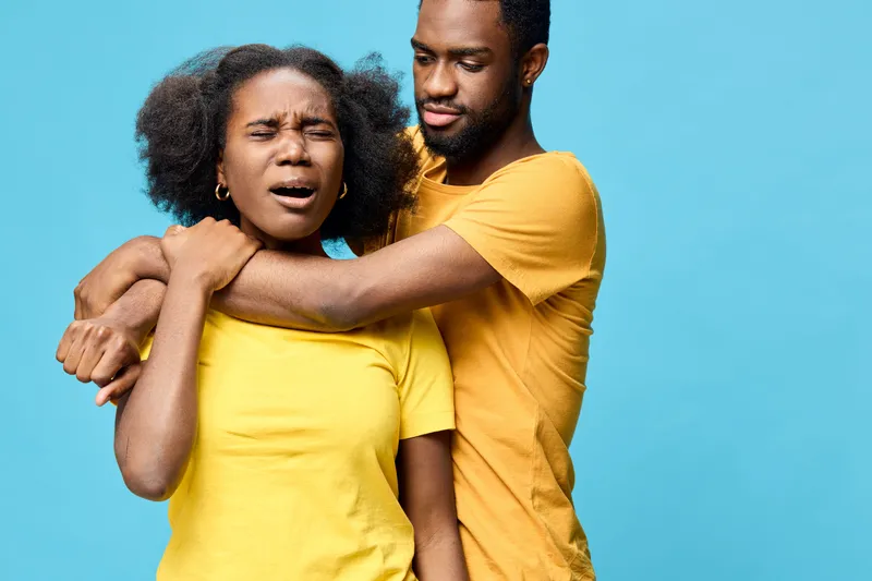 Emotional young Afro American couple in yellow shirts against a blue background, displaying feelings of discomfort and connection