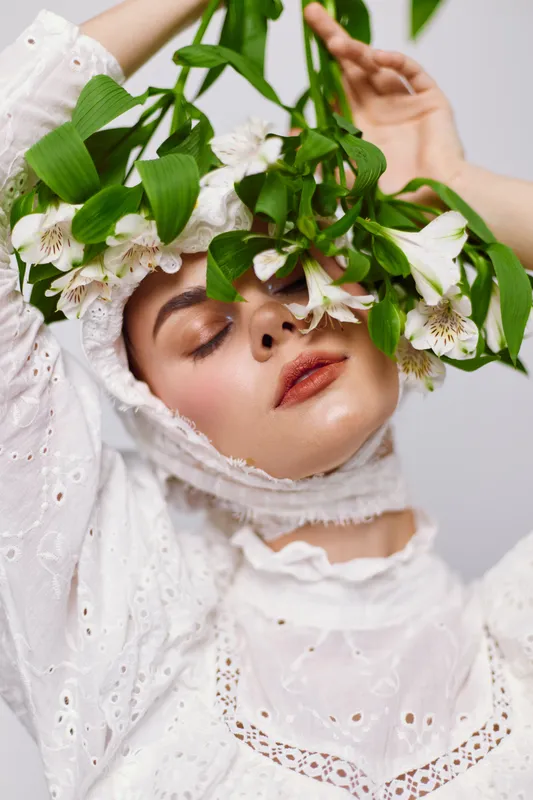 Beautiful woman in white attire with flowers, showcasing serene emotions and a fresh spring vibe, perfect for concepts of natural beauty and tranquility