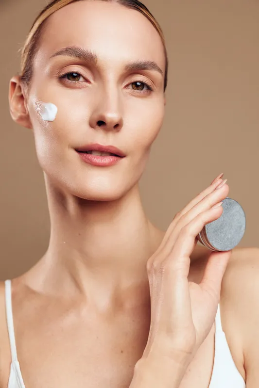 Woman skincare closeup, face treatment with cotton pad, beauty spa relaxation, smooth complexion and hydration, gentle routine, neutral beige background, natural light, calm expression