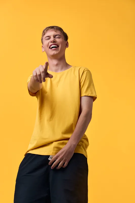 Laughter, expression, happiness, gesture, yellow, casual style, man pointing with a wide smile against a bright backdrop, energetic playful mood for lifestyle stock