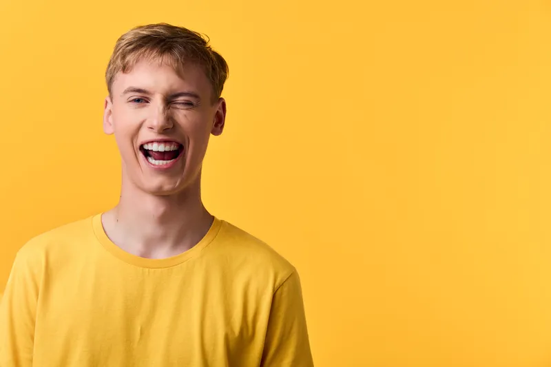Smiling man in a yellow shirt against a bright yellow background, conveying happiness and energy, casual lifestyle scene ideal for positivity, marketing and branding visuals