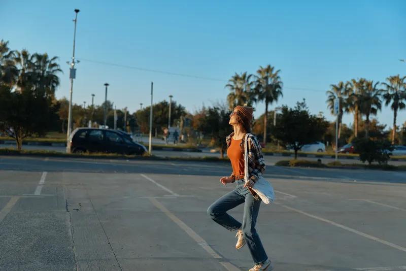 Woman jump in empty parking at golden light, candid joyful urban moment with casual denim outfit and authenticity, emotional storytelling capturing mindful living and free movement.