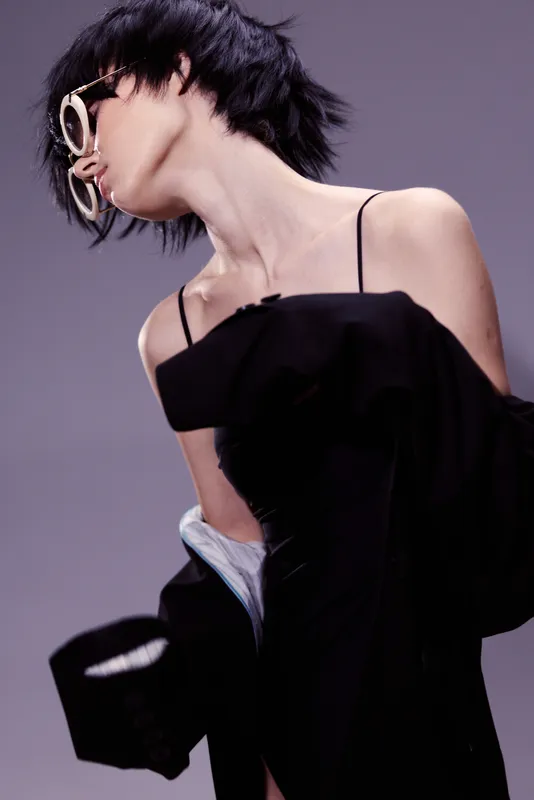 stylish woman in black dress with glasses posing with dramatic neck turn, fashion, elegance, modern style