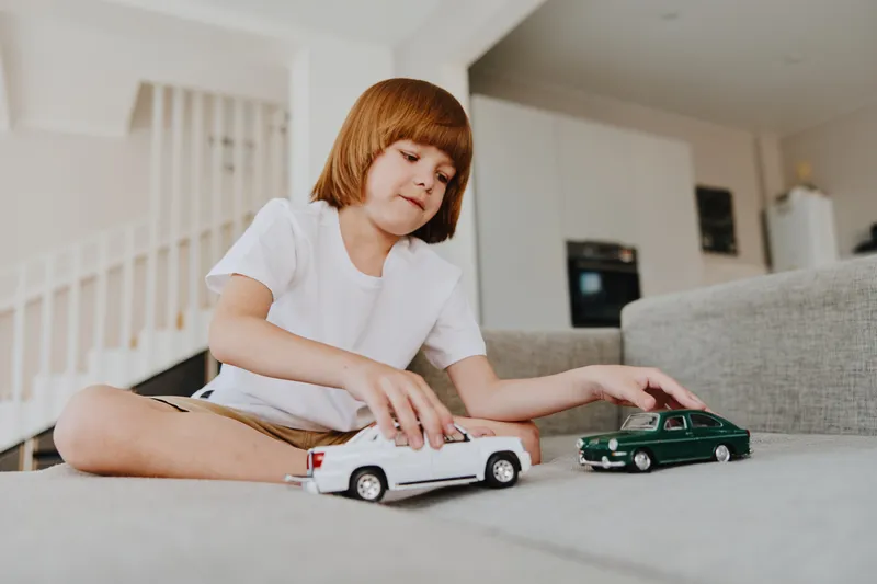 A young boy playing with toy cars in a cozy living room setting, showcasing creativity and imagination in a bright and cheerful atmosphere.