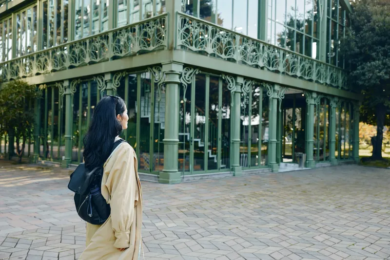 woman, backpack, travel, architecture, glass, building, exterior, urban, outdoor, exploration capture a quiet moment as she surveys ornate ironwork and reflective facade of a glass landmark