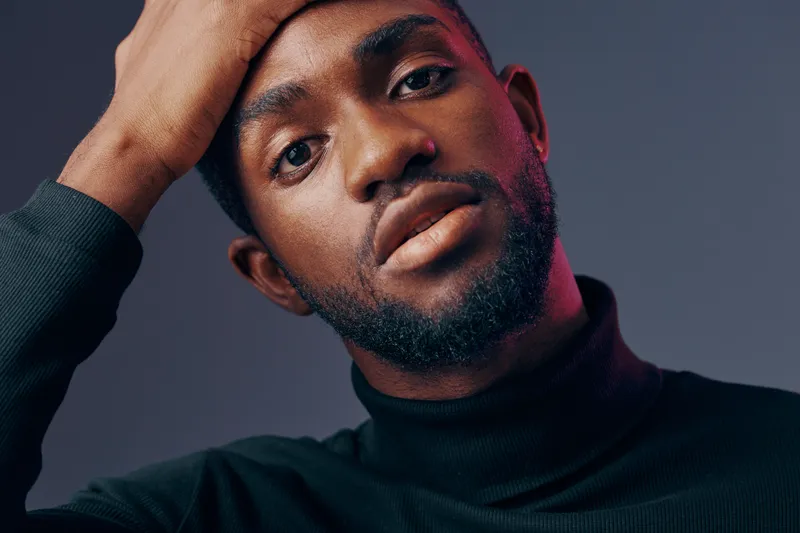 Confident young African man in a black turtleneck sweater with a thoughtful expression against a moody gradient background, showcasing contemporary fashion and self reflection