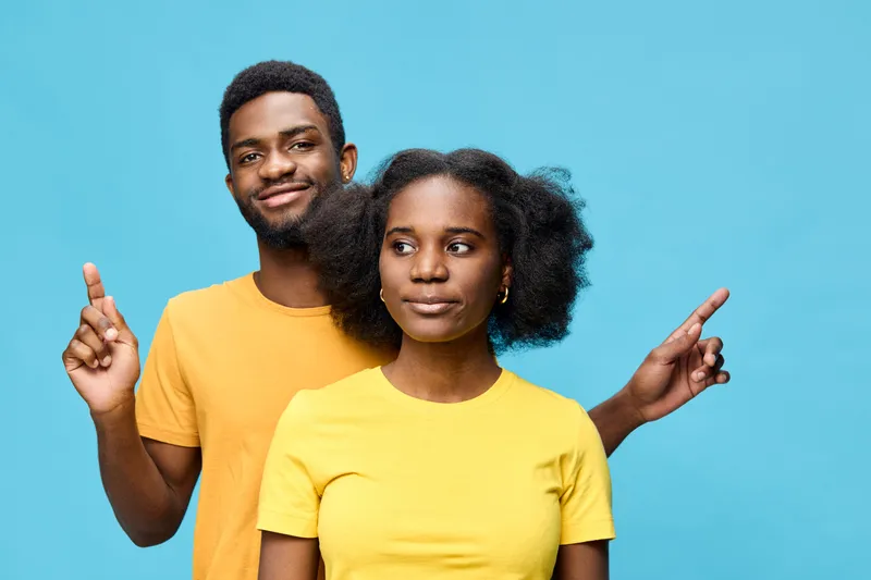 A cheerful couple in matching yellow shirts poses against a bright blue background, expressing joy and harmony with upbeat emotions and gestures