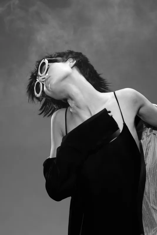 black and white woman wearing sunglasses and elegant dress posing against sky