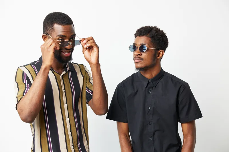 Stylish black men wearing sunglasses, showcasing modern fashion, confidence, and camaraderie in a minimalist setting, perfect for lifestyle promotions.