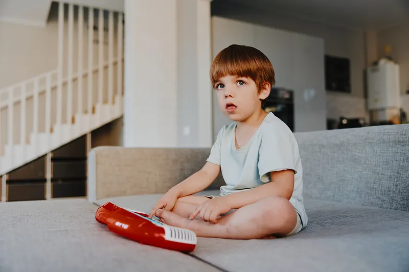 Curious boy playing with a toy keyboard in a cozy living room, showcasing creativity and focus in a relaxing atmosphere full of natural light.