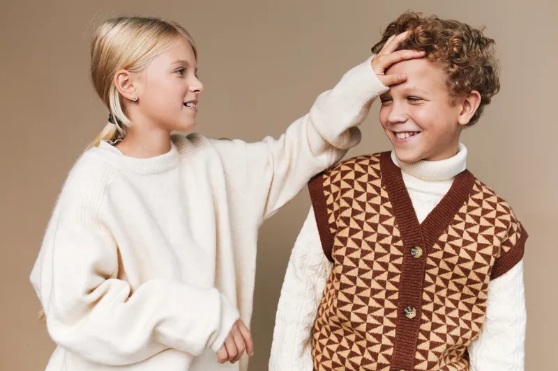 Authentic scene of two school-aged children playing together, cozy outfits, soft lighting, candid interaction, and a wholesome lifestyle moment focused on friendship and everyday school life.