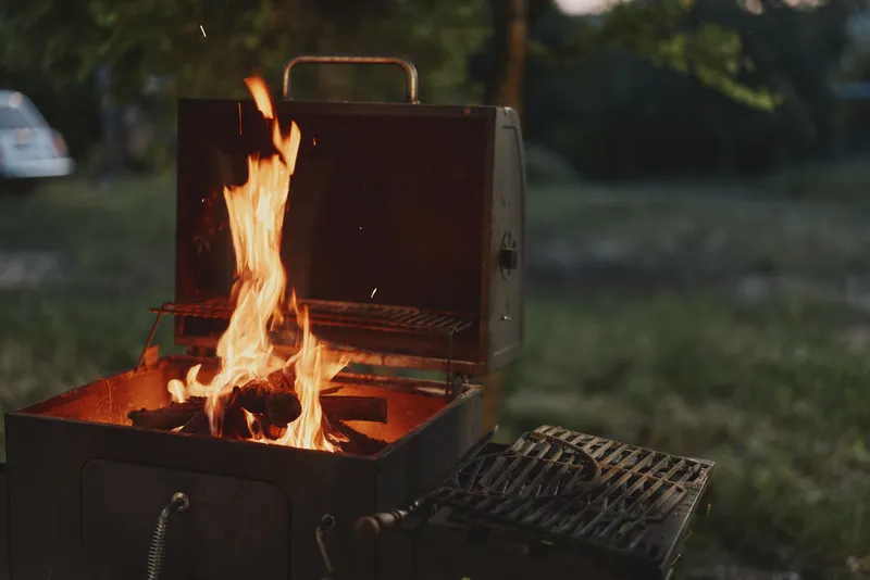 Cozy summer barbecue with vibrant flames in a grill, showcasing the joy of outdoor cooking and dining in a lush garden setting