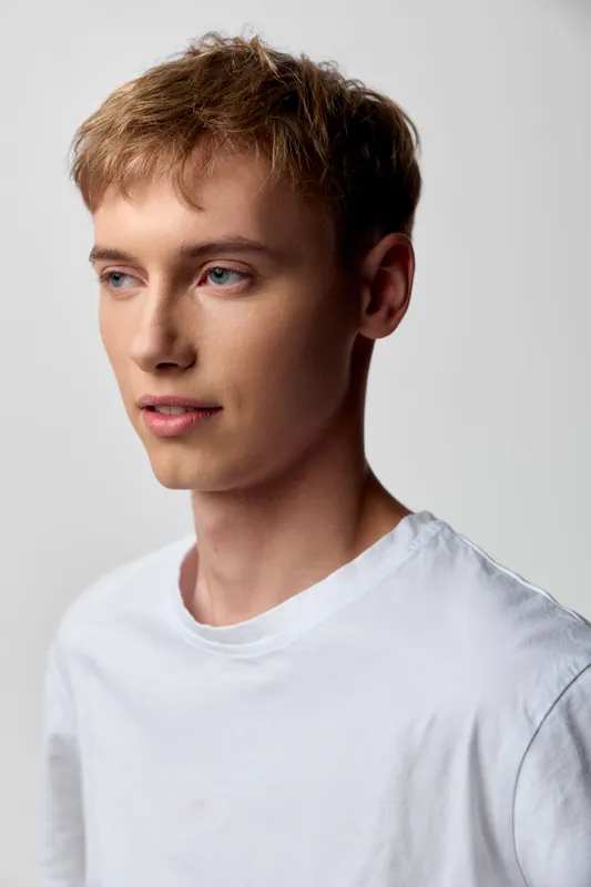 Youthful male in a white tee stands in a studio with soft lighting, calm expression and clean background, ideal for modeling and lifestyle use, a modern headshot with versatile, marketable appeal