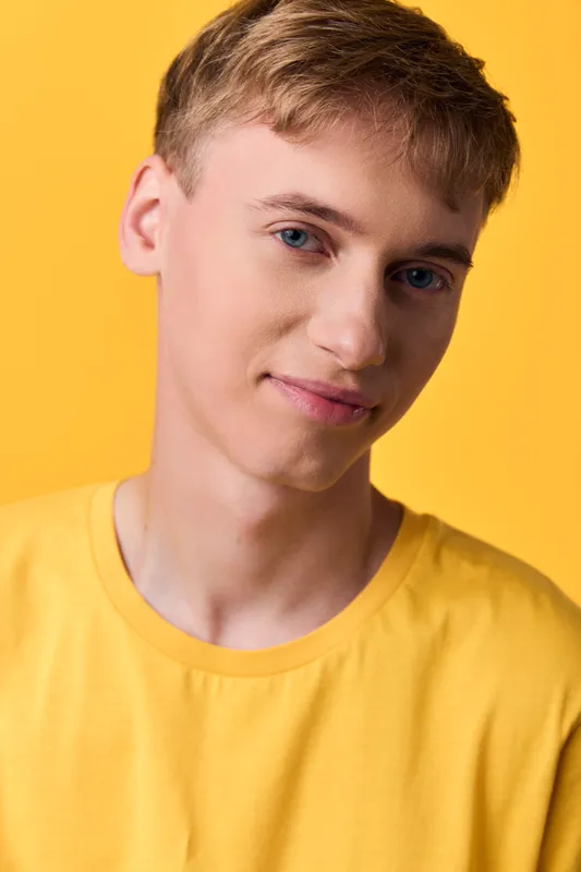 Close up of a cheerful young man in a yellow shirt against a bright background, casual lifestyle shot suited for fashion, positivity and everyday optimism