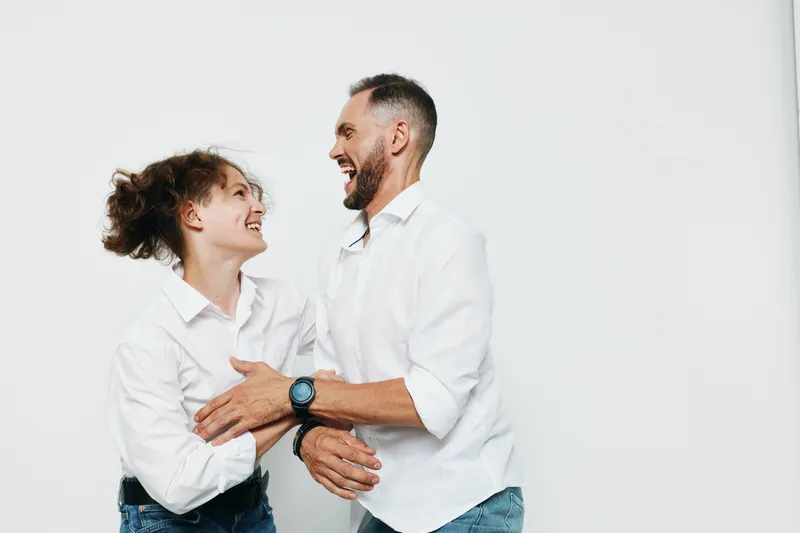 A professional man in a business setting shares a warm moment with a colleague, showing confident joy and engagement against an isolated colored background.