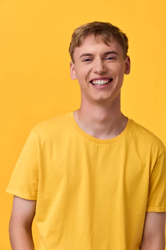 Smiling man in a bright yellow tee against a sunny backdrop, conveying cheerful energy, casual style, and friendly warmth suitable for lifestyle, fashion, and positivity themes