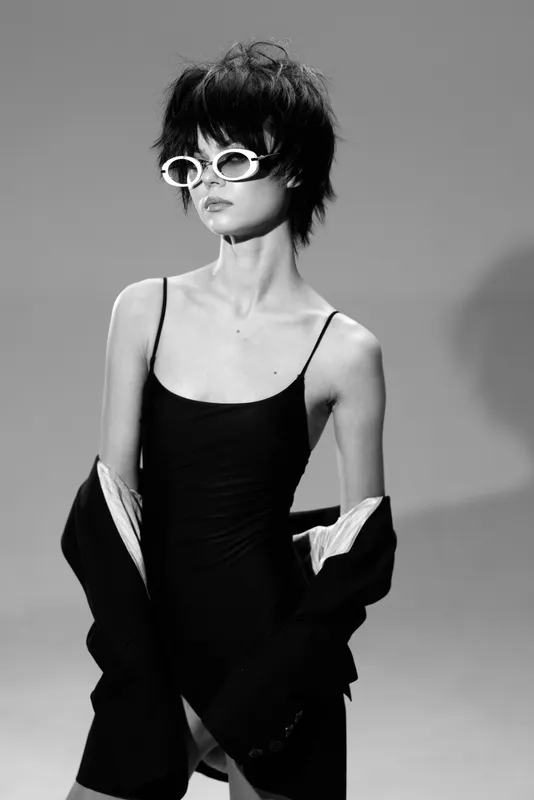 stylish woman wearing black dress and white sunglasses in black and white portrait with edgy look