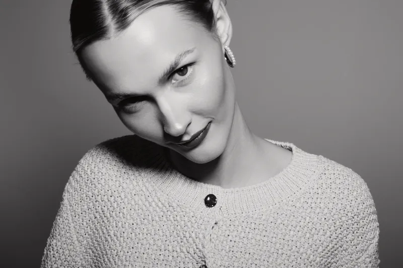 Portrait of a young Caucasian woman with fair skin smiling slightly in black and white studio lighting.