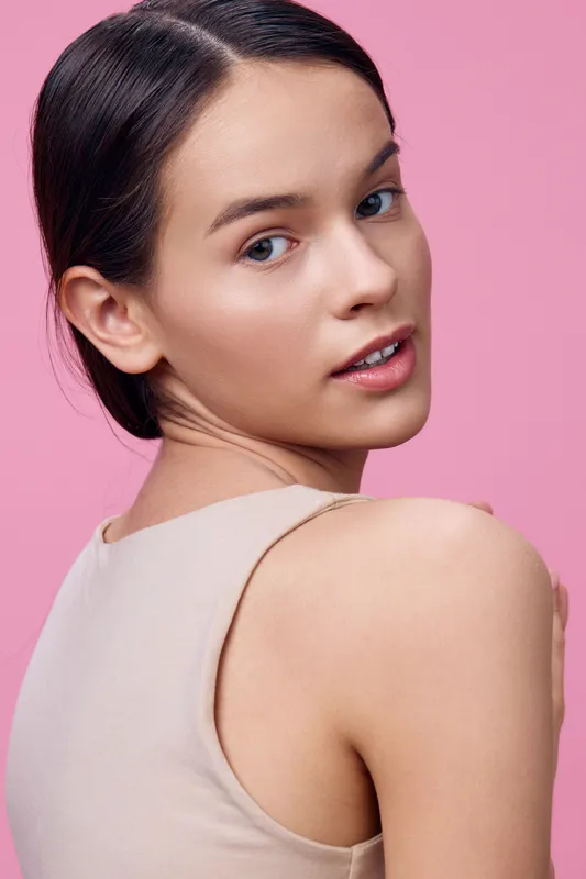 Young woman portrait on pink background, showcasing natural beauty with soft expression and minimal makeup Perfect for health and beauty themes