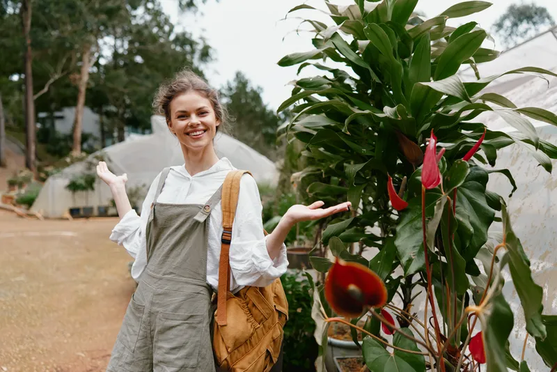 Young woman in overalls smiling in a garden, showcasing plants and nature, expressing joy and connection to the environment, with a warm color palette