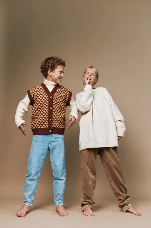Authentic lifestyle scene showing children in cozy school style outfits as they engage in playful game, friendship, and imagination, capturing natural candid moments.