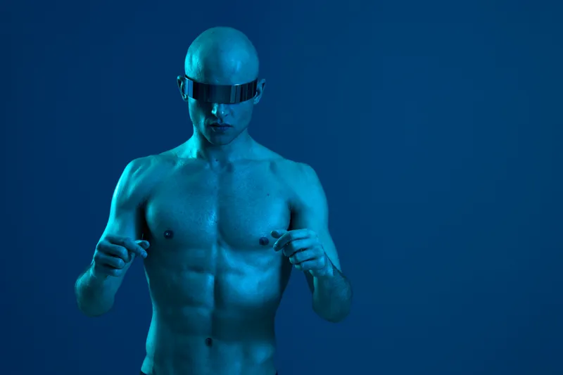 Athletic man in futuristic sunglasses, showcasing a unique style and bold vibe, captured against a blue background, exuding confidence and strength.