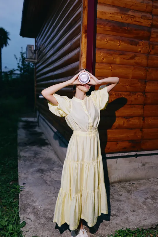 woman dress yellow wooden drink outdoors evening portrait by log wall with authenticity inclusivity candid rural