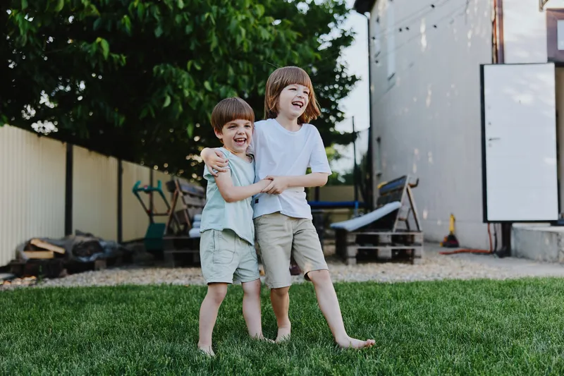 Happy kids playing outside in a bright green yard, enjoying the sunny day with laughter and joy, making unforgettable memories together.
