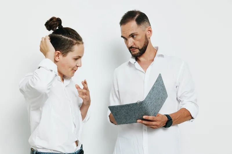 A professional man in a white shirt reviews a document with a focused expression against a solid colored background, conveying confidence and careful decision making.