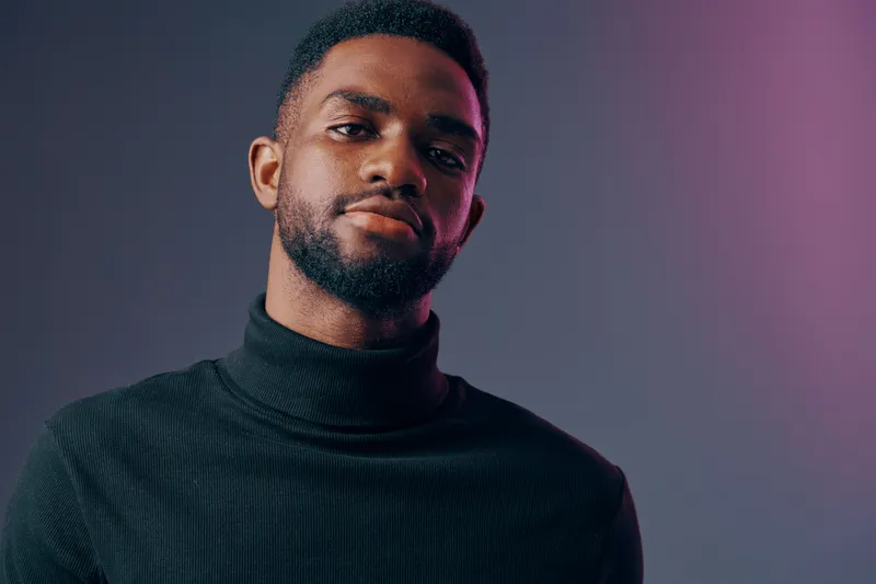 A confident young man models a black turtleneck sweater against a gradient background, exuding self assurance and style Ideal for fashion and lifestyle imagery