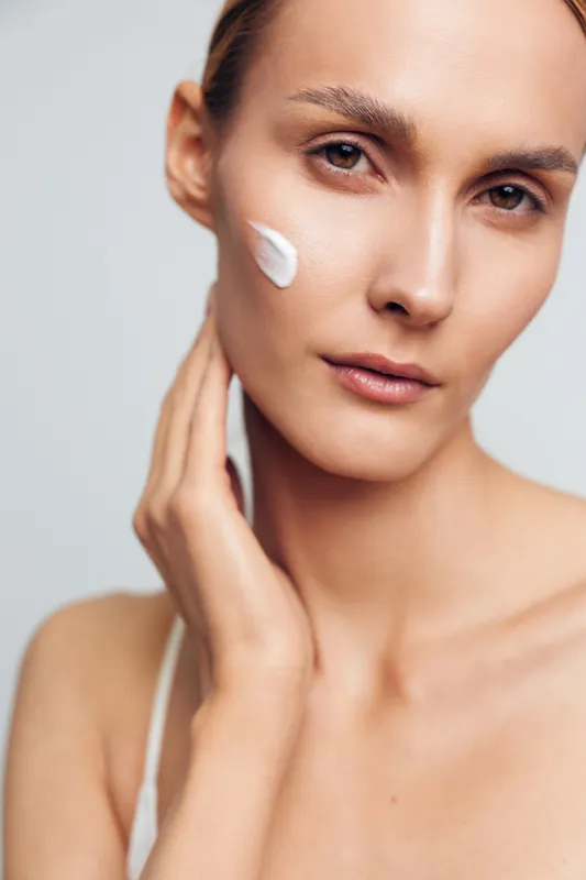 woman, closeup beauty portrait for skincare and spa wellness, cream for hydration on face, smooth skin, calm hands, gentle treatment, studio white background