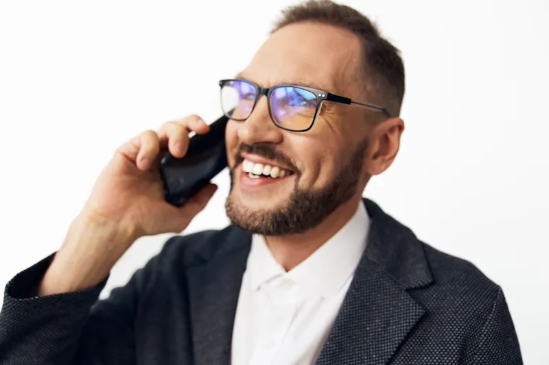 A professional businessman on a call, smiling with confidence against a colored isolated background, portraying focus, energy, and positive leadership in a modern work moment.