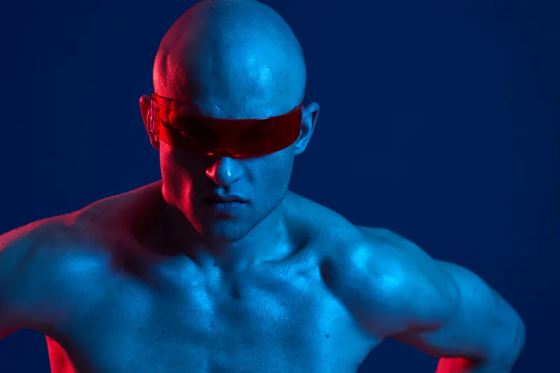 Strong man in futuristic sunglasses, showcasing intense expression, illuminated by red and blue neon lights. Black and white aspect adds dramatic contrast to the scene.