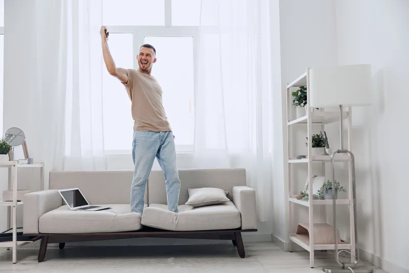 Happy man embracing a digital detox while celebrating personal choices at home. A moment of authentic imperfection in a calm and cozy setting.
