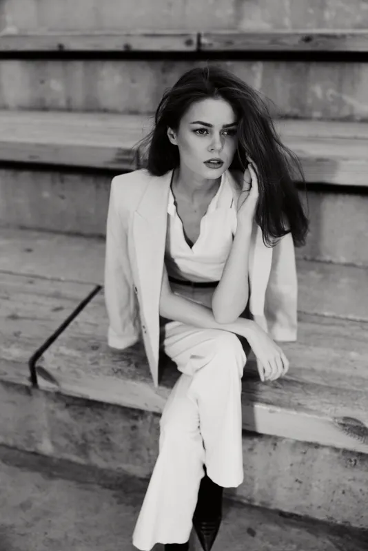 Woman in white business suit sitting on concrete stairs with thoughtful expression black and white fashion photography BUSINESS woman, white suit, sitting, thoughtful, black and white, stairs, fashion