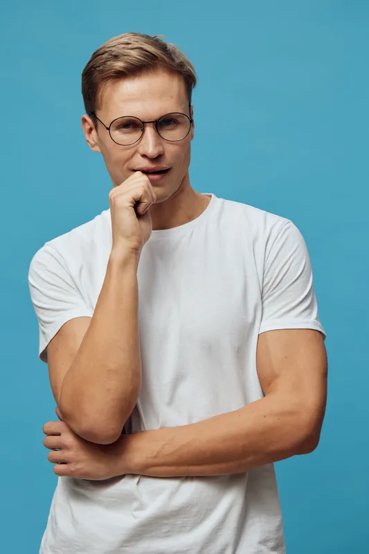 thoughtful man wear glasses and white t-shirt isolated on blue background digital detox concept mental health relaxation casual lifestyle portrait