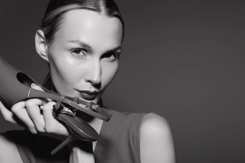 Close-up portrait of a fair-skinned Caucasian woman holding an accessory, with slicked-back hair against a dark background. Concept of fashion and elegance.
