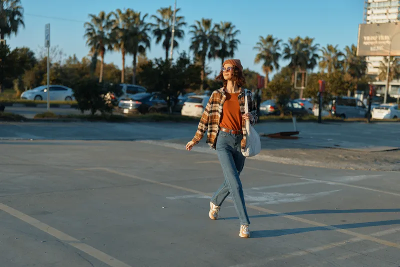 woman walking casual in an urban parking lot at golden hour, a candid lifestyle portrait blending authenticity, golden hour glow, mindful living and emotional storytelling in city streets