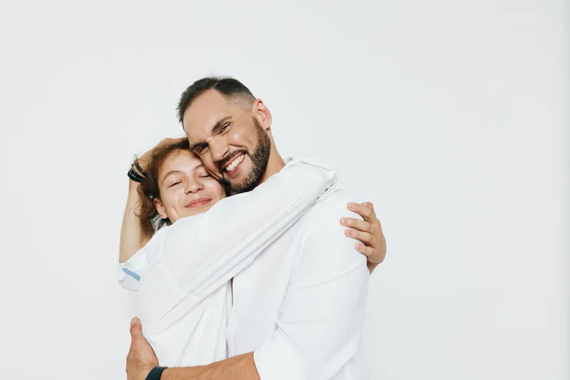 A business professional man embraces a colleague with a genuine smile against an isolated colored background, conveying confidence, warmth, and positive emotion.