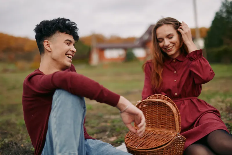 Two friends share a candid outdoor moment, smiling and relaxed, showcasing authenticity and veracity in genuine connection, simple joy, and natural emotion.