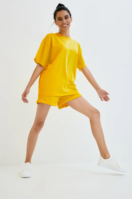 young woman wearing bright yellow casual outfit smiling with energetic pose on white background, athletic and happy lifestyle concept