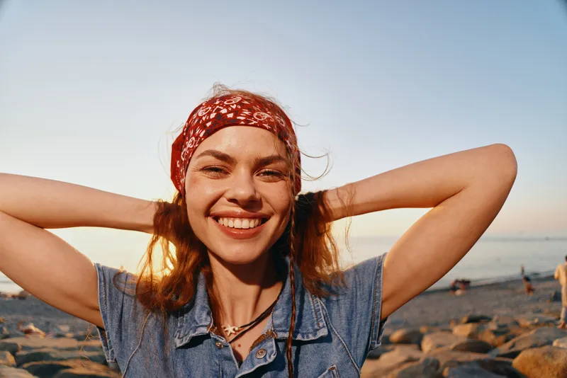 lifestyle woman smiling in modern boho-western denim street style with red bandana film color, bright natural light, sunny outdoor setting, warm tones