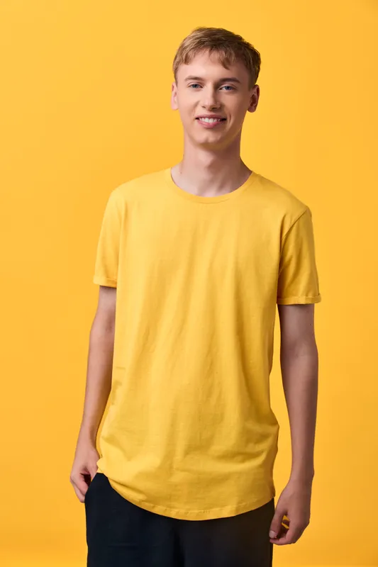 Yellow tshirt man in a bright studio, showcasing casual clothing and a friendly smile, lifestyle focused pose with a clean, vibrant background for contemporary fashion imagery