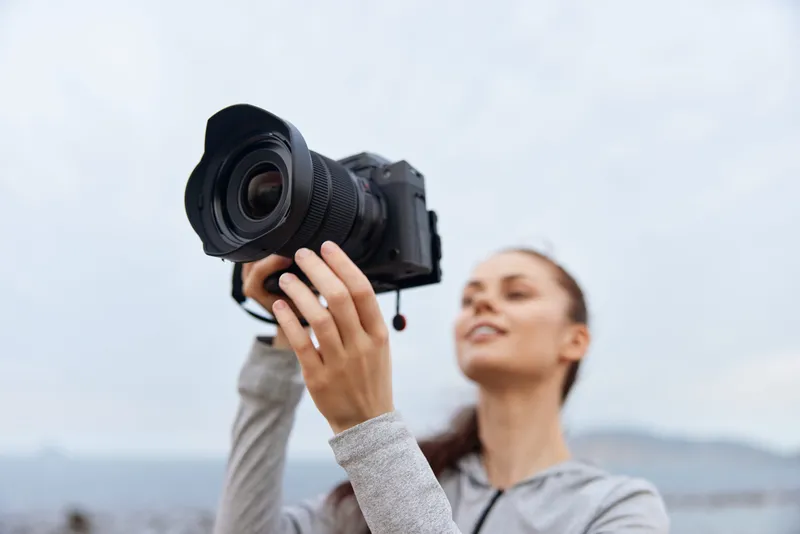 Young woman taking photos outdoors with a professional camera, wearing casual athletic clothing, expressing joy Ideal for photography and lifestyle concepts