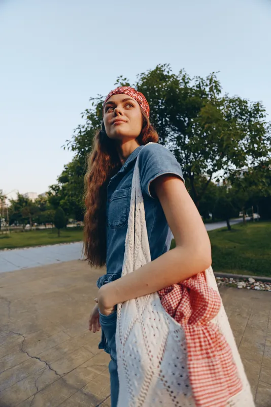 Lifestyle woman in modern boho-western denim street style outfit with bandana and tote bag, captured in warm film color outdoor setting.