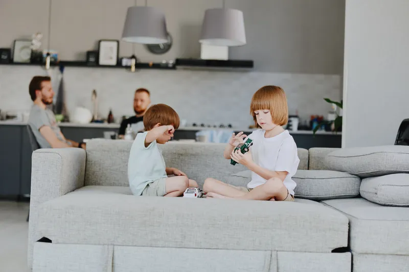 Playing children in a cozy living room with soft natural light, engaging with toys and enjoying family time together in a modern home setting.
