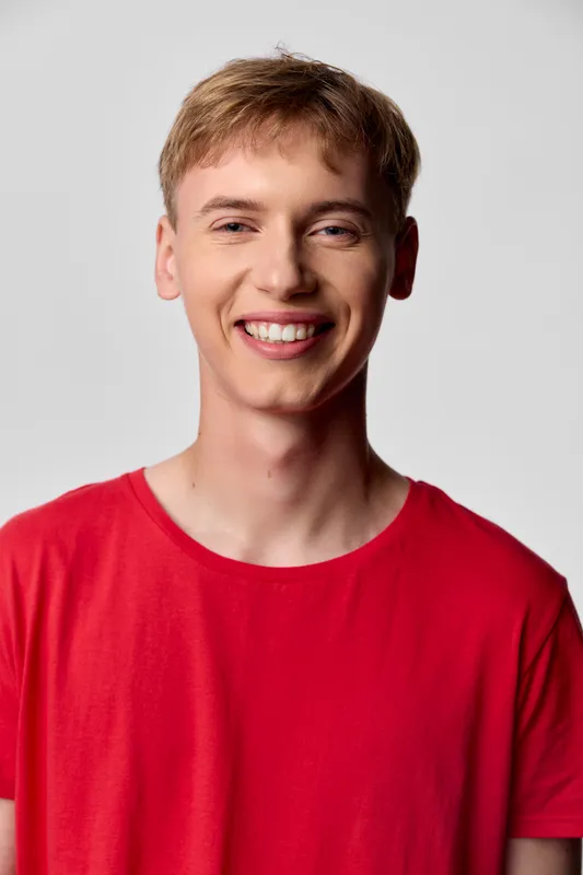Smiling young man in a red shirt with casual style and friendly vibe, studio lighting and bright backdrop for lifestyle, fashion, and modern usage with clean composition
