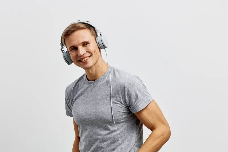 smiling man wearing headphones casual grey t-shirt enjoying music digital detox concept isolated on light background youthful lifestyle portrait